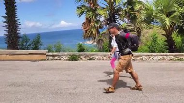 Bir erkek ve bir kadın, doğa güzelliği ve sükunetle çevrili bir yolda rahatça yürüyorlar..