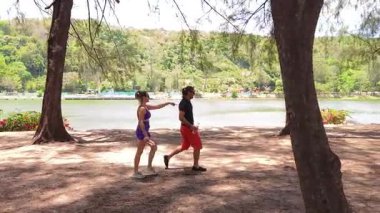 Bir adam ve bir kadın parkta birlikte esneme egzersizleri yapıyorlar..