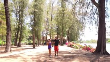 Bir adam ve genç bir kadın parkta badminton oynuyorlar..