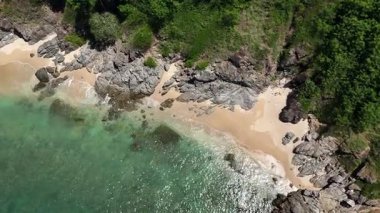 Göz kamaştırıcı bir hava manzarası, yemyeşil ağaçlar ve okyanuslarla çevrili pitoresk bir plajı sergiliyor..