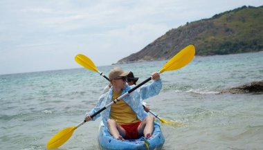 Genç çift, açık mavi bir kanoyla birlikte sarı raketlerle mutlu bir şekilde yol alıyorlar..