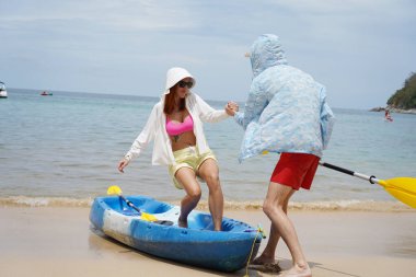 Genç bir çift deniz yolculuğundan sonra sudan bir kano çıkarıyorlar..