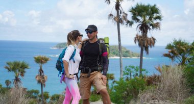 Genç bir çift okyanus manzarası sunan engebeli kayalık bir uçurumda yürüyüş yapıyor..