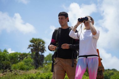 Bir erkek ve bir kadın dikkatle dürbünle uzaktan ilginç bir şeye bakıyorlar..