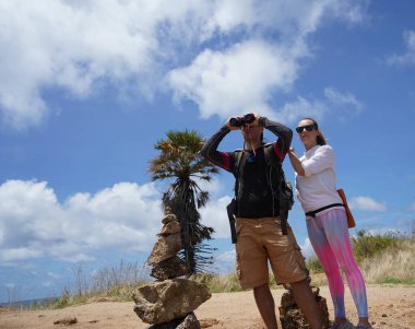 Bir erkek ve bir kadın dikkatle dürbünle uzaktan ilginç bir şeye bakıyorlar..