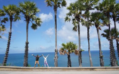 Muhteşem palmiye ağaçlarının önünde genç bir çift yan yana duruyor..