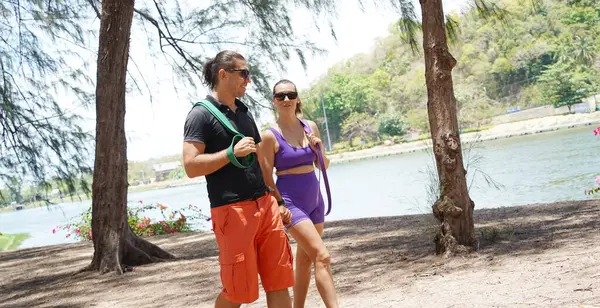 Genç çift parkta direniş bantlarıyla egzersiz yapıyor..