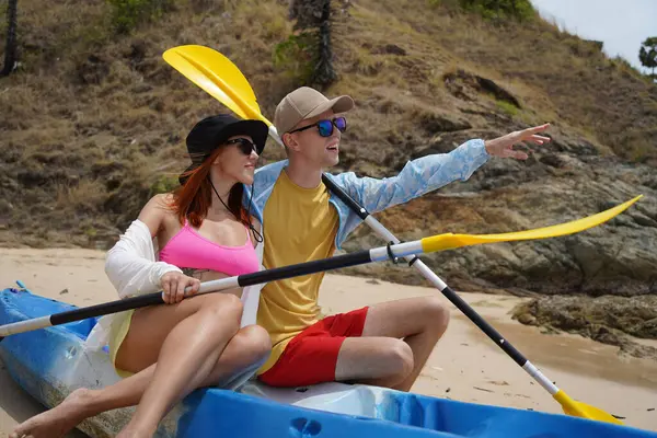 Kumsalda genç bir çift ellerinde kano kürekleri ve suda eğlenceli bir yolculuğa hazırlar..