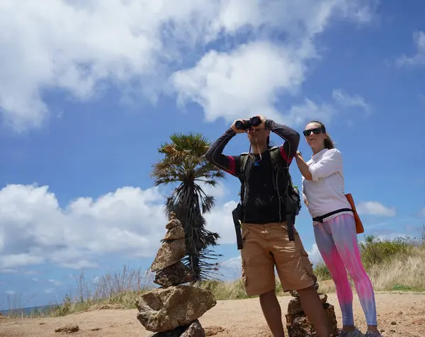 Bir erkek ve bir kadın dikkatle dürbünle uzaktan ilginç bir şeye bakıyorlar..