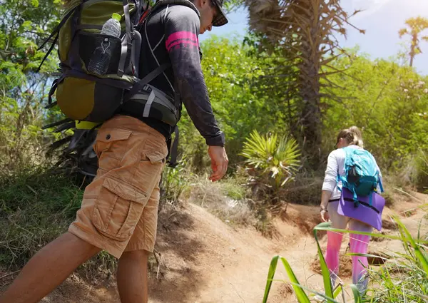 Genç bir çift okyanus manzarası sunan engebeli kayalık bir uçurumda yürüyüş yapıyor..