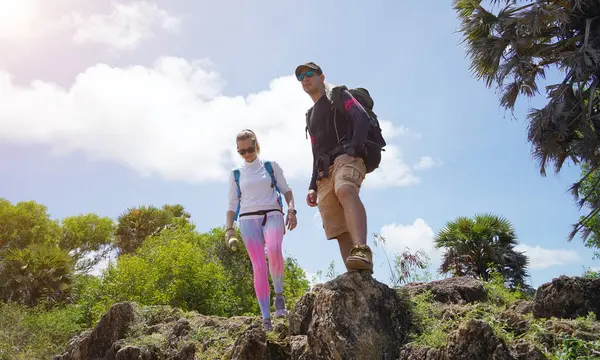Genç bir çift okyanus manzarası sunan engebeli kayalık bir uçurumda yürüyüş yapıyor..