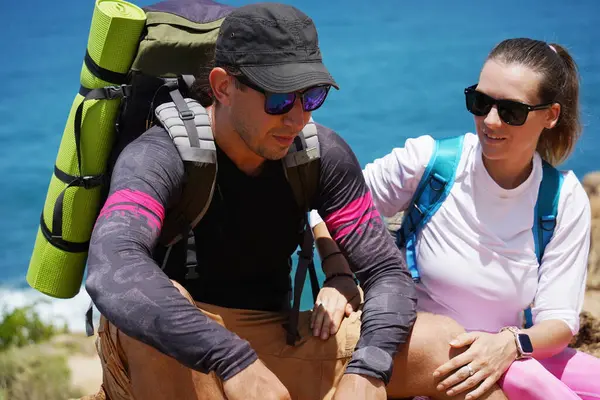 Genç bir çift okyanus manzarası sunan engebeli kayalık bir uçurumda yürüyüş yapıyor..