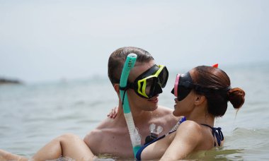 Bir adam ve bir kadın gözlük takıyor ve suyun tadını çıkarıyorlar..