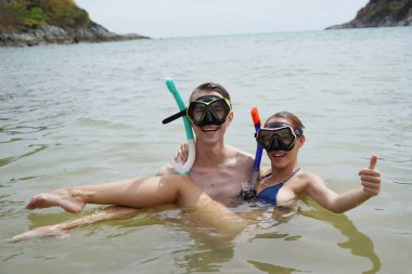 Bir adam ve bir kadın gözlük takıyor ve suyun tadını çıkarıyorlar..