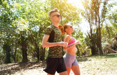 Bir adam ve bir kadın güzel bir parkta birlikte koşuyorlar, temiz havanın tadını çıkarıyorlar.