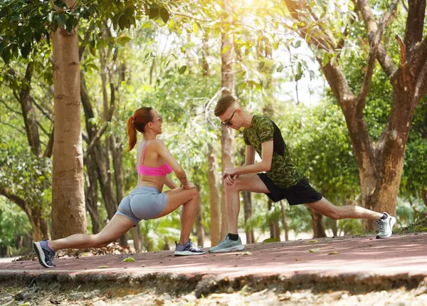 Bir adam ve bir kadın parkta birlikte koştuktan sonra bacaklarını açıyorlar..