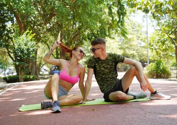 Parkta şık güneş gözlüğü takan bir adam ve bir kadın..