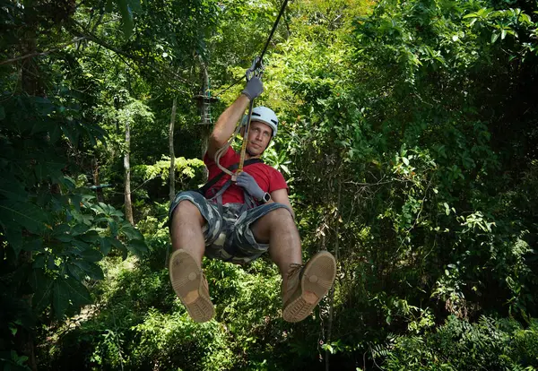İnsanoğlu, etrafını saran kalın ormandan geçen bir ip üzerinde keyifli bir yolculuğun tadını çıkarıyor..