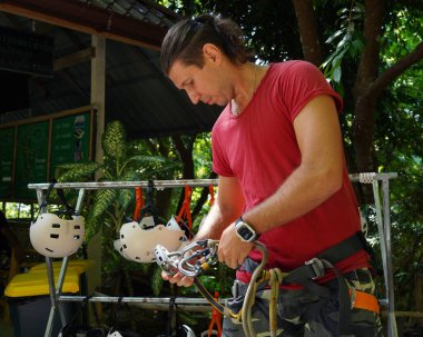 Bir adam heyecanlı bir tırmanışa dikkatle hazırlanır, güvenliğini sağlar..