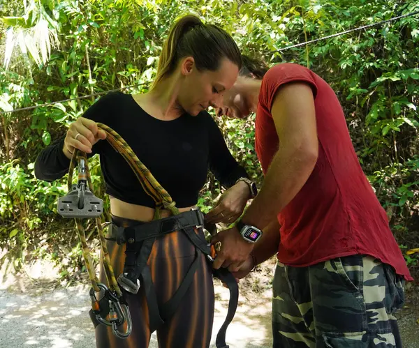 Bir erkek, halatla kaymadan önce bir kadına güvenlik amacıyla yardım ediyor..