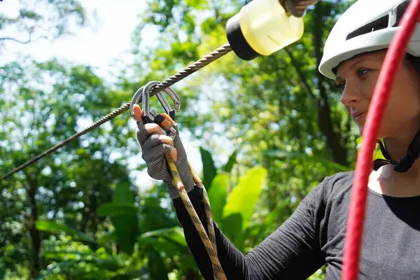 Kadın, etrafını saran kalın ormandan geçen bir halatla neşeli bir yolculuğun tadını çıkarıyor..