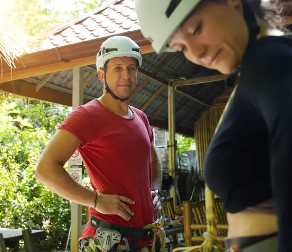 Bir erkek, halatla kaymadan önce bir kadına güvenlik amacıyla yardım ediyor..