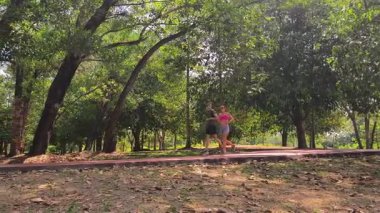 Bir adam ve bir kadın güzel bir parkta birlikte koşuyorlar, temiz havanın tadını çıkarıyorlar.