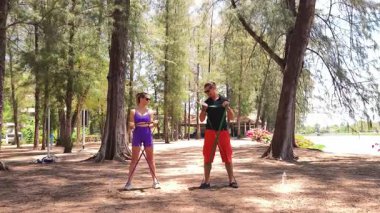 Genç çift parkta direniş bantlarıyla egzersiz yapıyor..