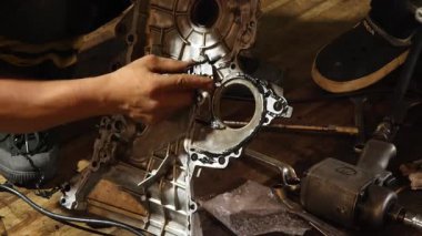 Servis elemanı özenle garajın içindeki bir araba motoru üzerinde çalışıyor..