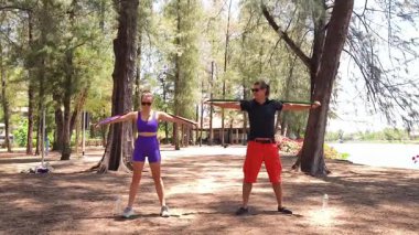 Genç çift parkta direniş bantlarıyla egzersiz yapıyor..