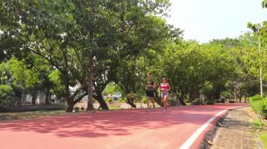 Bir adam ve bir kadın güzel bir parkta birlikte koşuyorlar, temiz havanın tadını çıkarıyorlar.