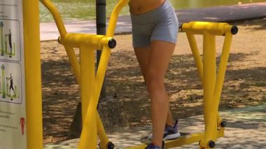 Bir adam ve kadın parkta bir makinede birlikte egzersiz yapıyorlar..