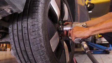 Yetenekli bir tamirci, güvenlik ve bakım sağlamak için lastik değiştirmek için elektrikli bir araç kullanır..