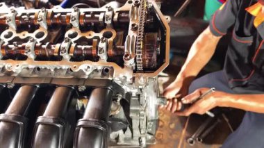 Servis elemanı özenle garajın içindeki bir araba motoru üzerinde çalışıyor..