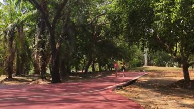Bir adam ve bir kadın güzel bir parkta birlikte koşuyorlar, temiz havanın tadını çıkarıyorlar.