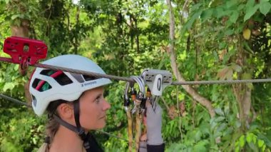 Kadın, etrafını saran kalın ormandan geçen bir halatla neşeli bir yolculuğun tadını çıkarıyor..