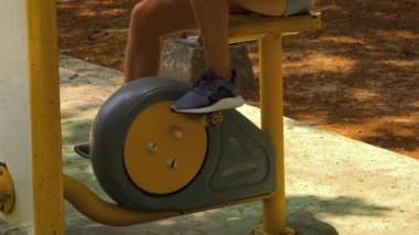 Bir adam ve kadın parkta bir makinede birlikte egzersiz yapıyorlar..