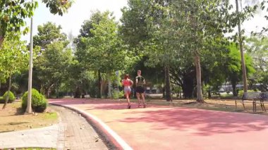 Bir adam ve bir kadın güzel bir parkta birlikte koşuyorlar, temiz havanın tadını çıkarıyorlar.