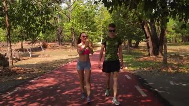 Bir adam ve bir kadın güzel bir parkta birlikte koşuyorlar, temiz havanın tadını çıkarıyorlar.