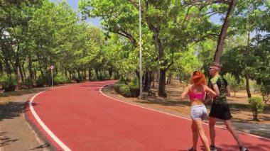 Bir adam ve bir kadın güzel bir parkta birlikte koşuyorlar, temiz havanın tadını çıkarıyorlar.