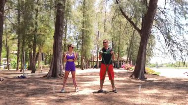 Genç çift parkta direniş bantlarıyla egzersiz yapıyor..