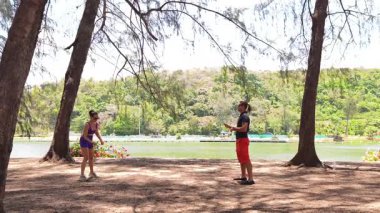 Bir adam ve genç bir kadın parkta badminton oynuyorlar..