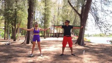 Genç çift parkta direniş bantlarıyla egzersiz yapıyor..
