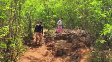 Genç bir çift okyanus manzarası sunan engebeli kayalık bir uçurumda yürüyüş yapıyor..