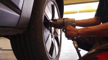 Yetenekli bir tamirci, güvenlik ve bakım sağlamak için lastik değiştirmek için elektrikli bir araç kullanır..