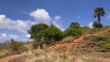 Genç bir çift okyanus manzarası sunan engebeli kayalık bir uçurumda yürüyüş yapıyor..