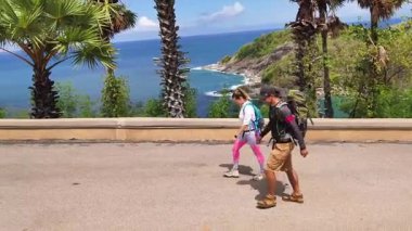 Bir erkek ve bir kadın, doğa güzelliği ve sükunetle çevrili bir yolda rahatça yürüyorlar..