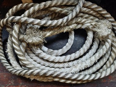 Bir denizci halatları ahşap bir zemine seriliyor..