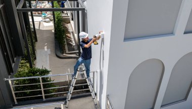 Bir teknisyen konut binasının ön cephesine kamera yerleştiriyor..