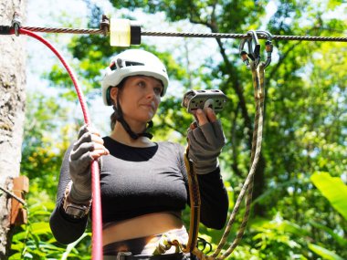 Kadın, etrafını saran kalın ormandan geçen bir halatla neşeli bir yolculuğun tadını çıkarıyor..